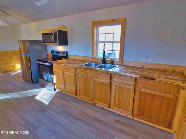 kitchen featuring appliances with stainless steel finishes, butcher block countertops, light hardwood / wood-style flooring, and sink