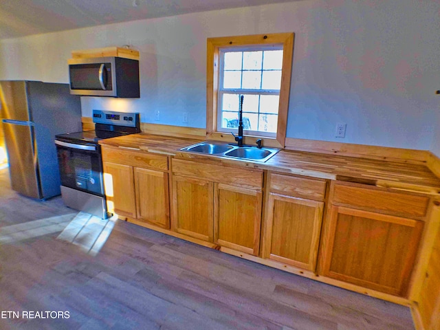 kitchen featuring wooden counters, stainless steel appliances, light hardwood / wood-style floors, and sink