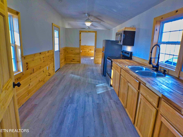 kitchen with stainless steel appliances, wooden walls, dark wood-type flooring, sink, and butcher block countertops