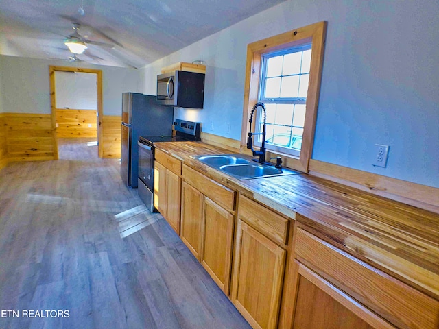 kitchen with wooden counters, wood-type flooring, stainless steel appliances, and sink