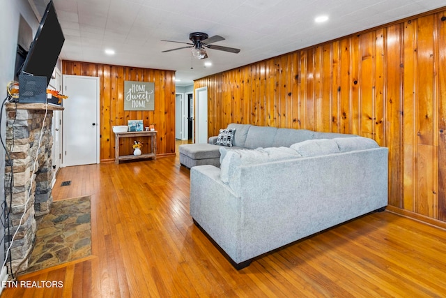 living room with wooden walls, ceiling fan, and hardwood / wood-style flooring