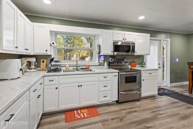 kitchen featuring appliances with stainless steel finishes, light hardwood / wood-style floors, white cabinetry, and sink