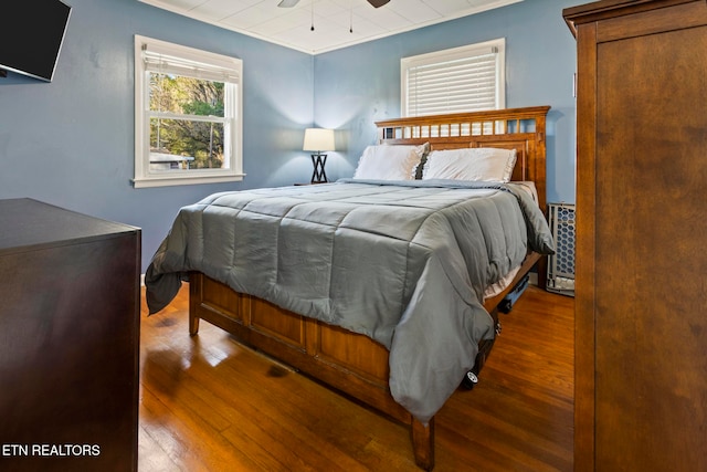 bedroom with hardwood / wood-style floors, ceiling fan, and ornamental molding