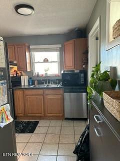 kitchen with dishwasher, light tile patterned floors, sink, and fridge