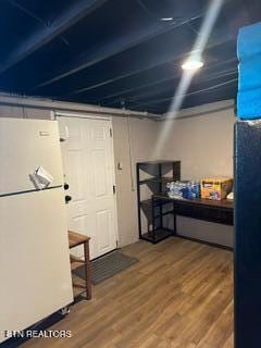 basement with hardwood / wood-style floors and white fridge