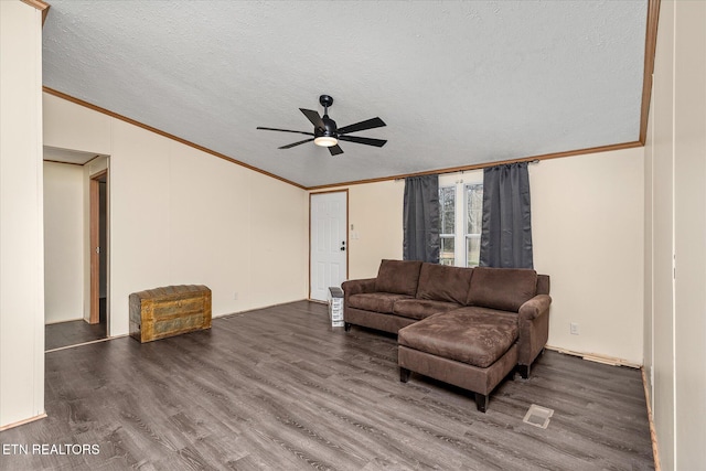 living room with a textured ceiling, ceiling fan, ornamental molding, and dark wood-type flooring