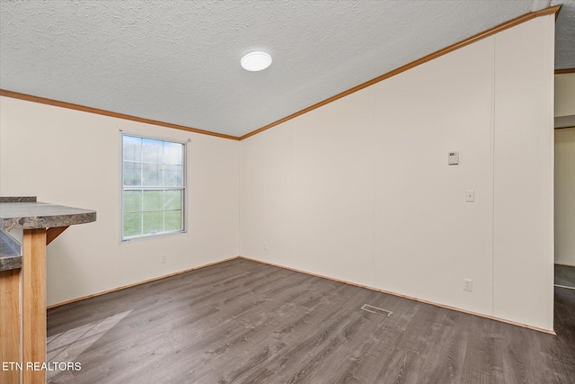 unfurnished living room featuring lofted ceiling, crown molding, dark wood-type flooring, and a textured ceiling