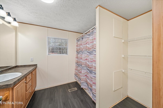 bathroom with vanity, wood-type flooring, a textured ceiling, and ornamental molding