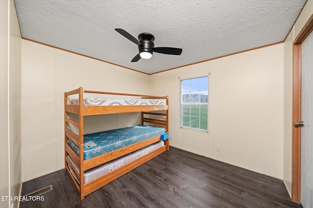 bedroom featuring a textured ceiling, ceiling fan, dark hardwood / wood-style floors, and ornamental molding