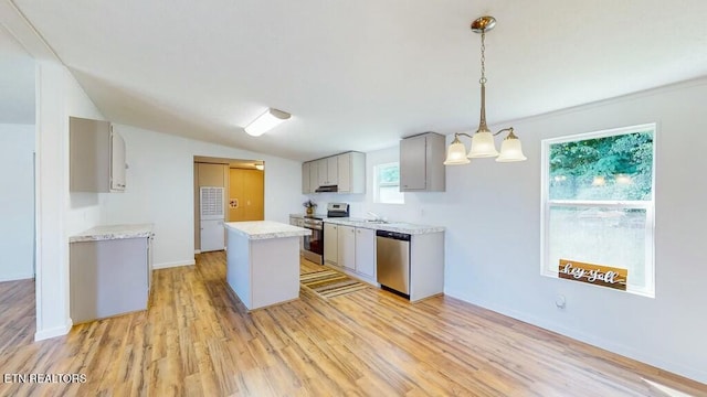 kitchen featuring decorative light fixtures, a center island, gray cabinets, stainless steel appliances, and light hardwood / wood-style floors