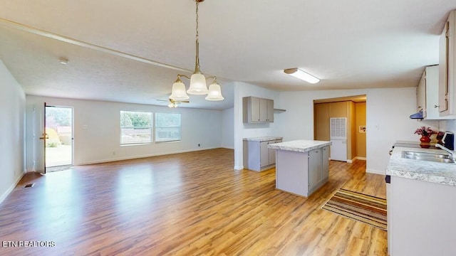 kitchen with a kitchen island, decorative light fixtures, sink, gray cabinetry, and light wood-type flooring