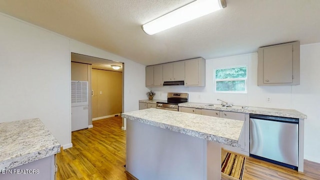 kitchen featuring appliances with stainless steel finishes, lofted ceiling, sink, gray cabinetry, and light hardwood / wood-style flooring