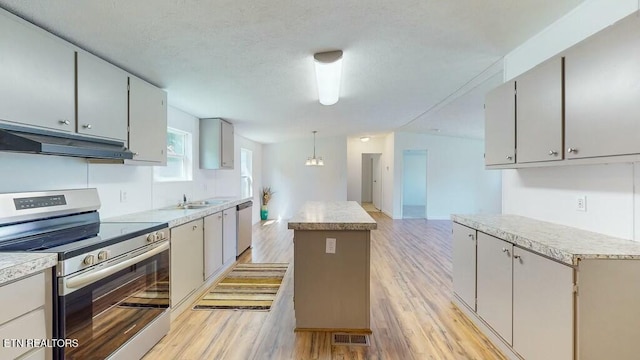 kitchen with gray cabinets, a kitchen island, hanging light fixtures, stainless steel appliances, and light hardwood / wood-style flooring