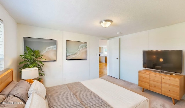 bedroom featuring light carpet and a textured ceiling