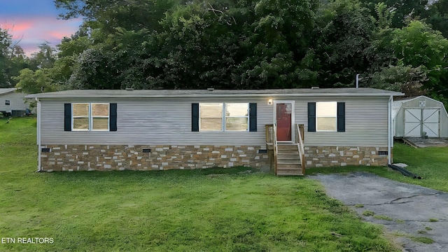 manufactured / mobile home featuring a shed and a yard