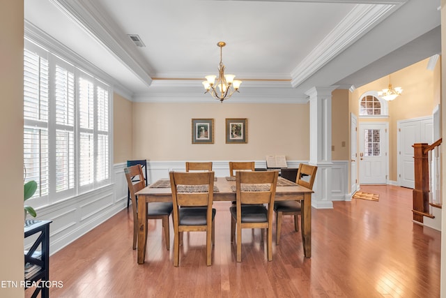 dining area with hardwood / wood-style floors, plenty of natural light, decorative columns, and an inviting chandelier