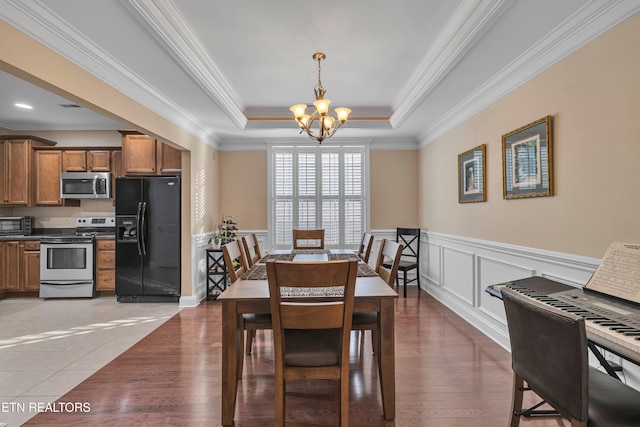 dining space featuring hardwood / wood-style floors, crown molding, a tray ceiling, and a chandelier