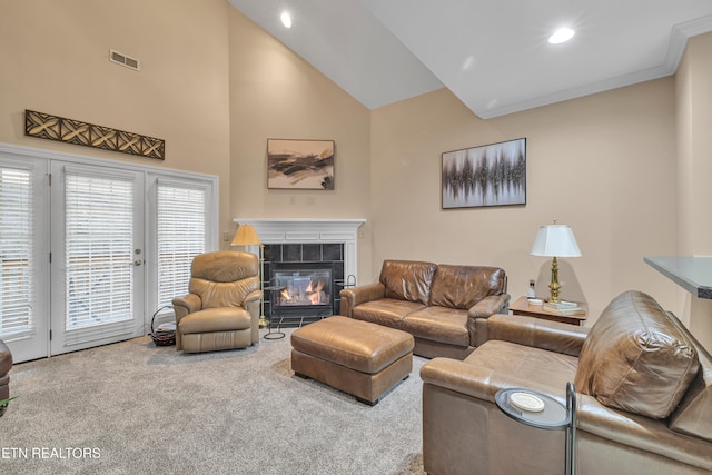 carpeted living room with a tile fireplace, high vaulted ceiling, and ornamental molding