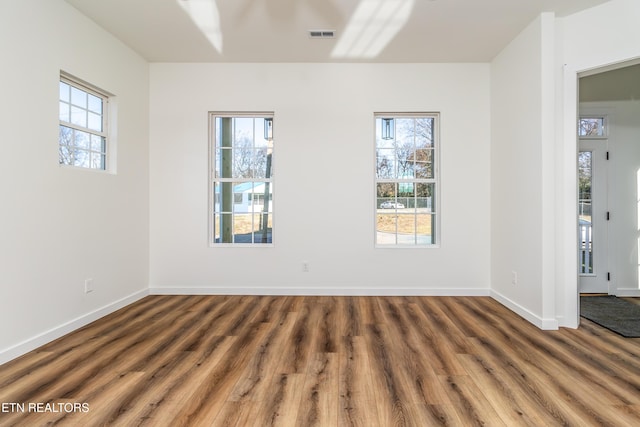 spare room featuring dark hardwood / wood-style floors, a wealth of natural light, and ceiling fan