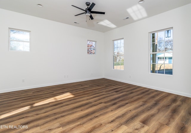 spare room with ceiling fan, a healthy amount of sunlight, and dark hardwood / wood-style floors