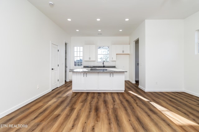 kitchen featuring sink, stone counters, a center island, dark hardwood / wood-style floors, and white cabinetry