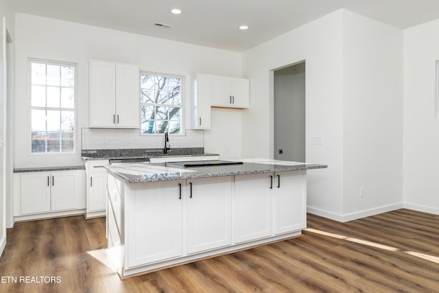 kitchen with white cabinets, a wealth of natural light, a kitchen island, and dark hardwood / wood-style floors