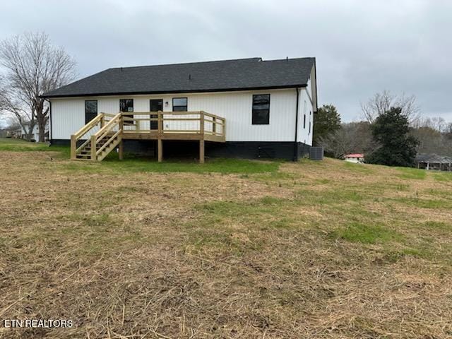 rear view of property featuring a lawn, central AC unit, and a deck