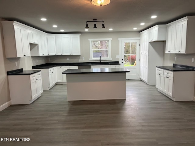 kitchen with white cabinets, a center island, dark hardwood / wood-style flooring, and sink