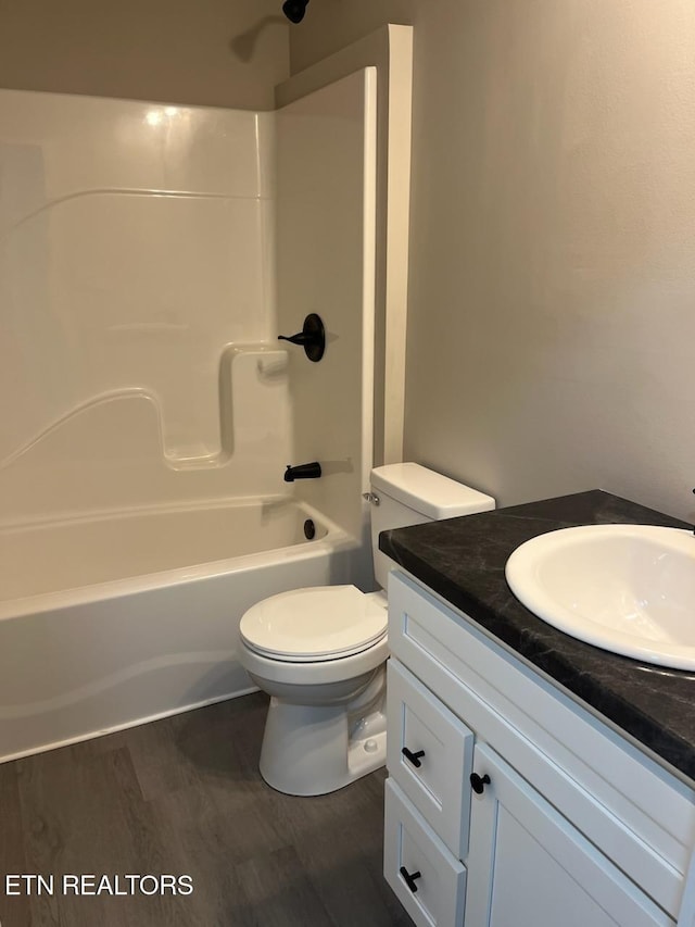 full bathroom featuring washtub / shower combination, vanity, wood-type flooring, and toilet