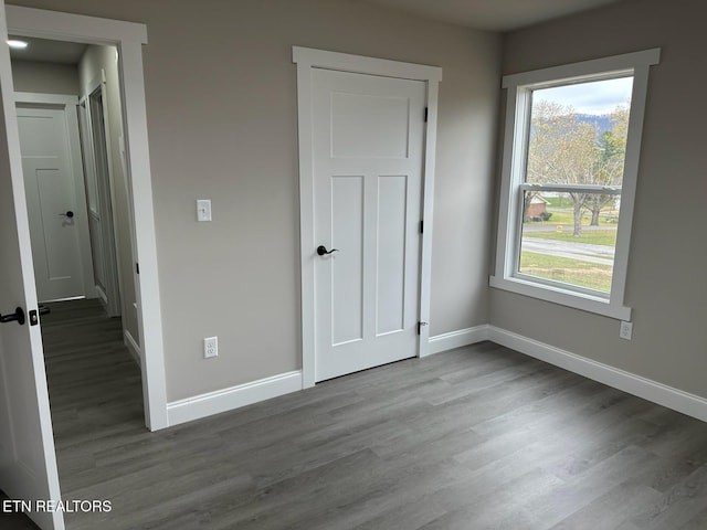 unfurnished bedroom with hardwood / wood-style flooring and multiple windows