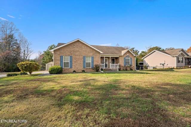 ranch-style home with a porch, an outdoor structure, and a front yard