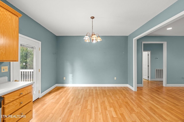 unfurnished dining area with light hardwood / wood-style flooring and a notable chandelier