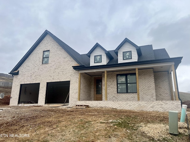 view of front of house featuring covered porch, brick siding, and an attached garage