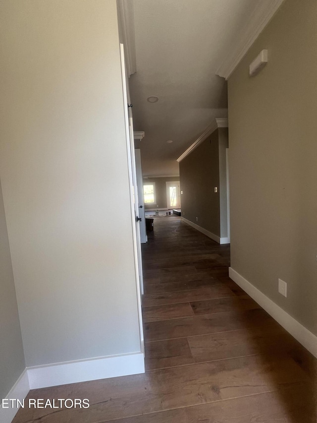 corridor featuring baseboards, dark wood-type flooring, and crown molding