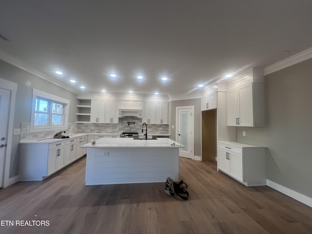 kitchen with a center island with sink, open shelves, light countertops, white cabinetry, and a sink