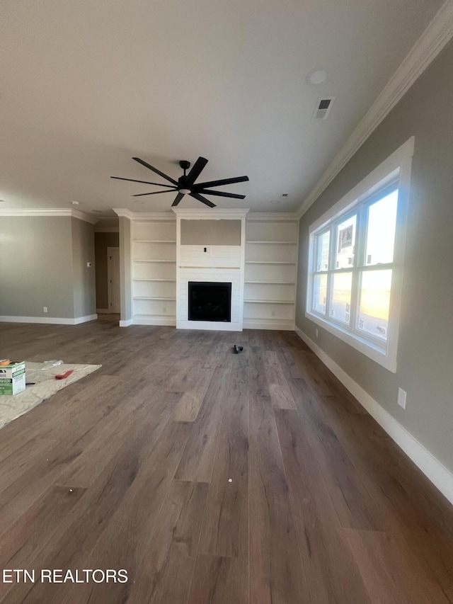 unfurnished living room featuring a fireplace, wood finished floors, visible vents, baseboards, and ornamental molding