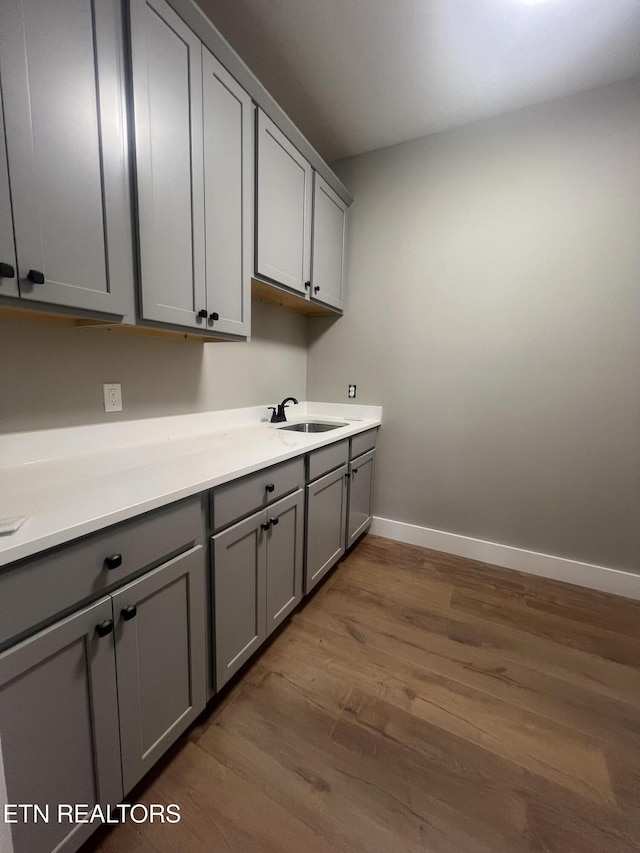 laundry area with baseboards, dark wood-style flooring, and a sink