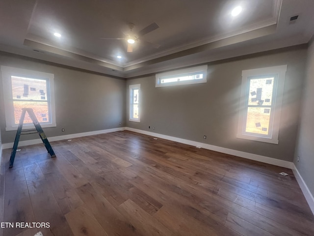 spare room featuring ornamental molding, dark wood-style flooring, a raised ceiling, and baseboards