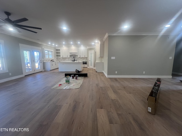 unfurnished living room with ceiling fan, recessed lighting, baseboards, light wood-type flooring, and crown molding