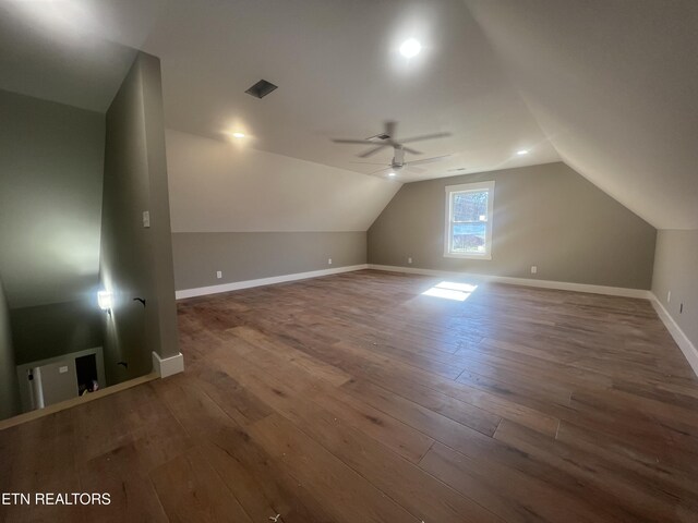 additional living space with vaulted ceiling, wood finished floors, visible vents, and baseboards