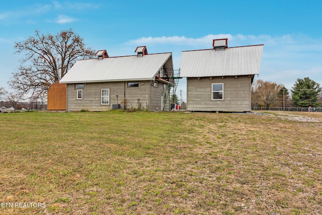 back of property featuring an outbuilding, central AC, and a lawn