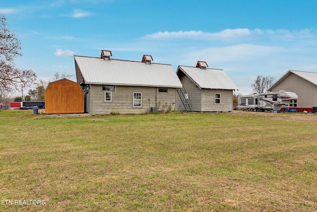 back of house featuring a storage unit, a yard, and central air condition unit