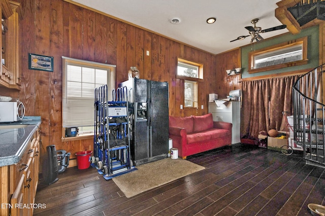 kitchen with black fridge with ice dispenser, wooden walls, dark wood-type flooring, and a healthy amount of sunlight