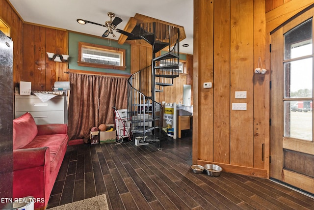 interior space featuring ceiling fan, dark wood-type flooring, and wood walls