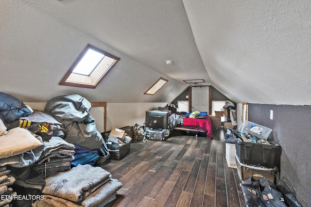 interior space featuring plenty of natural light, vaulted ceiling with skylight, a textured ceiling, and hardwood / wood-style flooring