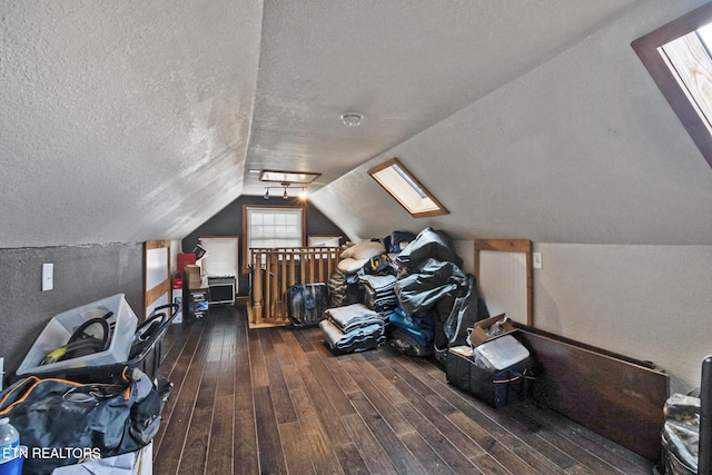 additional living space featuring a textured ceiling, lofted ceiling with skylight, and dark wood-type flooring