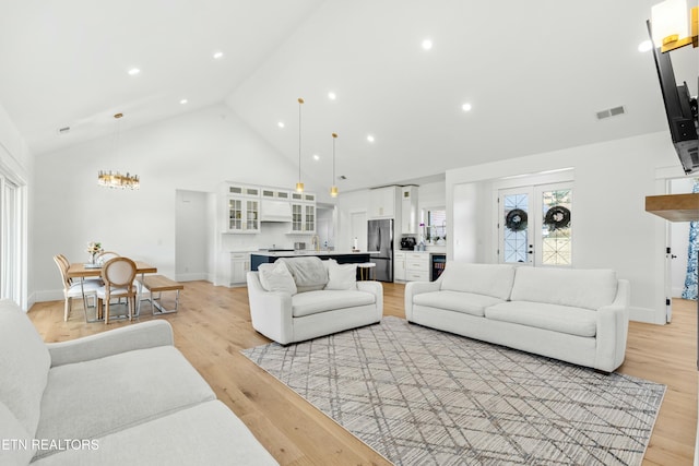 living room featuring light wood-type flooring and high vaulted ceiling