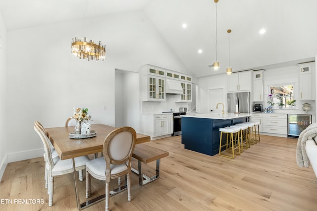 dining space featuring light hardwood / wood-style flooring, high vaulted ceiling, and beverage cooler