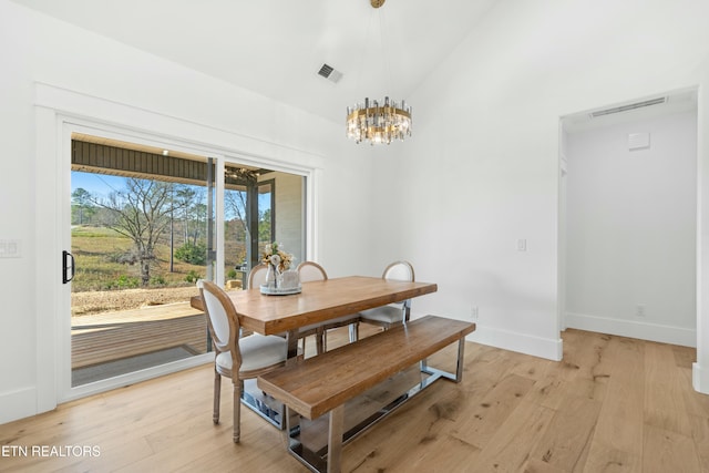 dining room featuring an inviting chandelier, light wood-type flooring, and vaulted ceiling