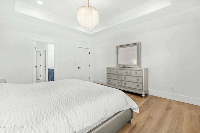 bedroom with a tray ceiling, crown molding, hardwood / wood-style floors, and a notable chandelier